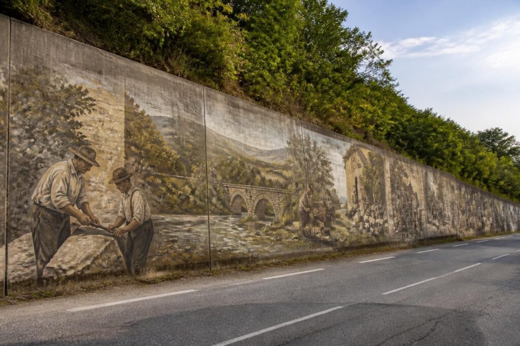 découvrez comment un mur de béton le long de la d55b au poizat-lalleyriat a été métamorphosé en une galerie d'histoire en plein air, alliant art et patrimoine local.
